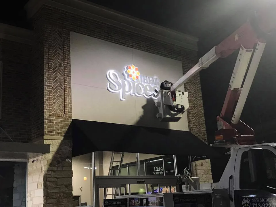 Lift truck positioned beside illuminated building lettering during installation