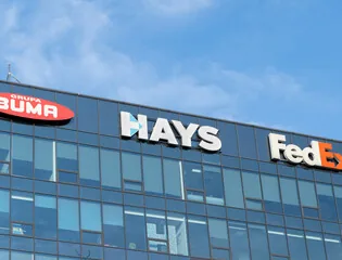 Large brand lettering mounted near the roofline of a glazed office building